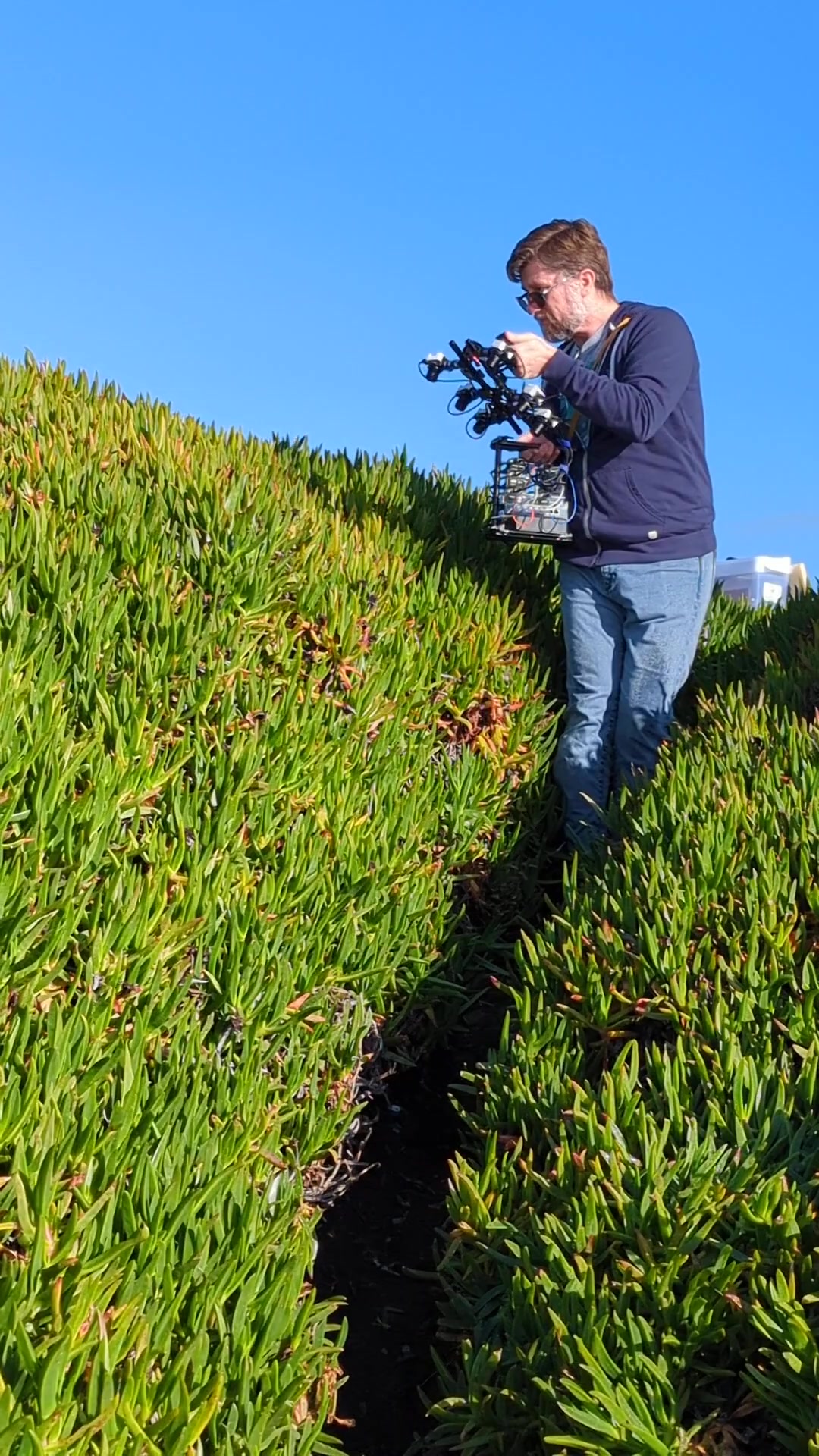 Rob Russell carrying gammacam P6 among some green vegetation