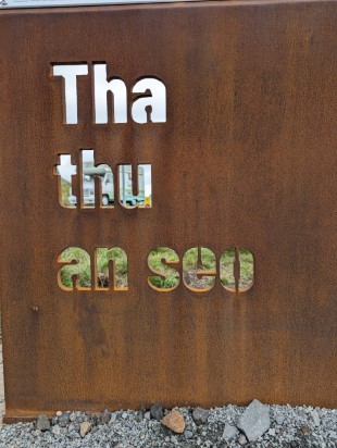 Rusted iron sign with the message Tha Thu An Seo cut into it